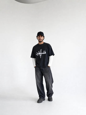 Person wearing a black t-shirt with white text and graphics, standing against a plain background